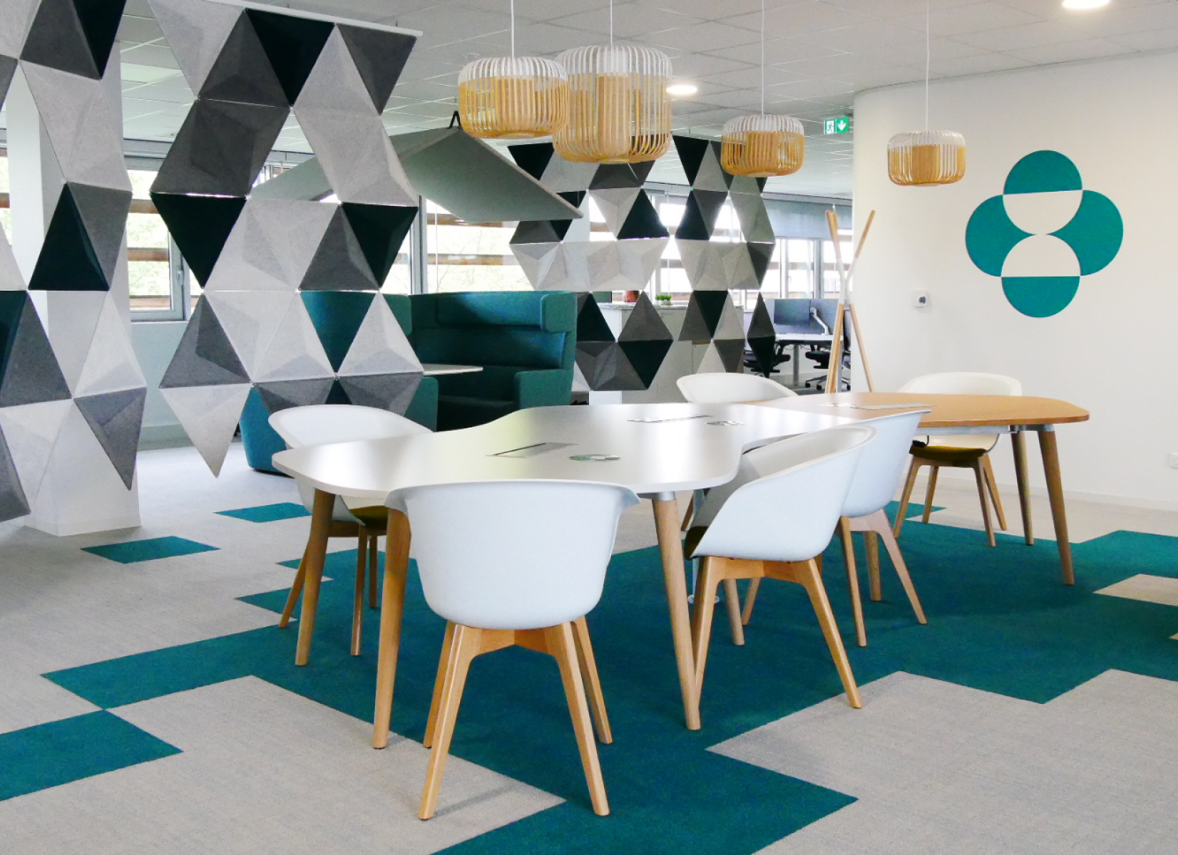 Bureaux collaboratifs MSD Santé Animale Espace de travail collaboratif moderne chez MSD avec mobilier design, chaises blanches, tapis sarcelle et cloisons acoustiques géométriques.