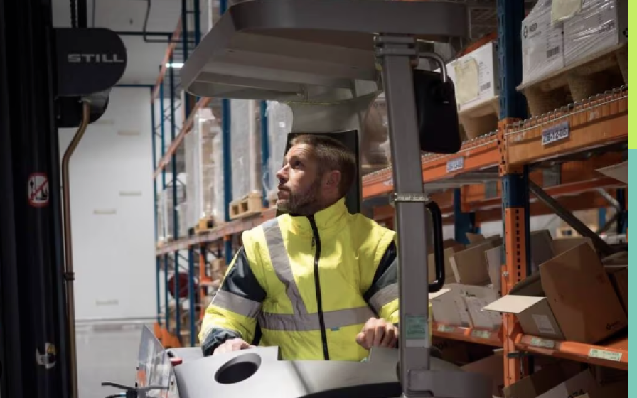 Opérateur de chariot élévateur en entrepôt logistique Employé conduisant un chariot élévateur dans un entrepôt, portant une veste de sécurité haute visibilité